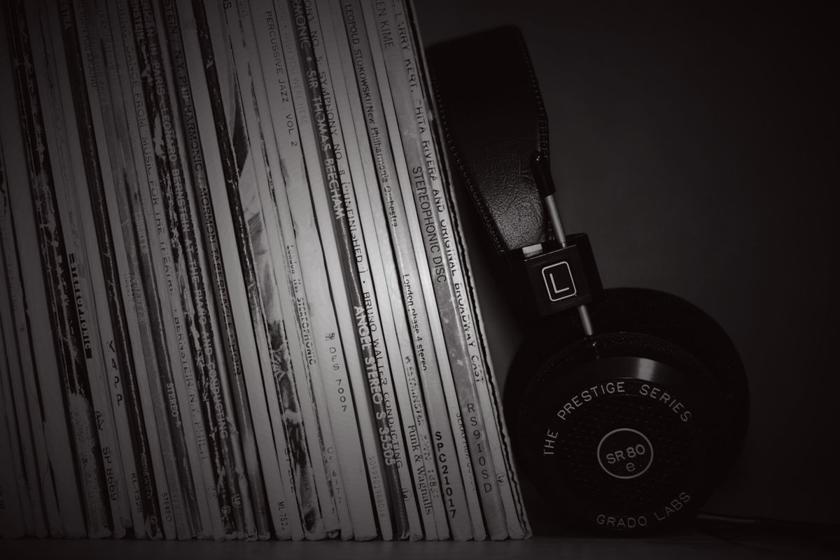 A rack of vinyl records beside a pair of headphones