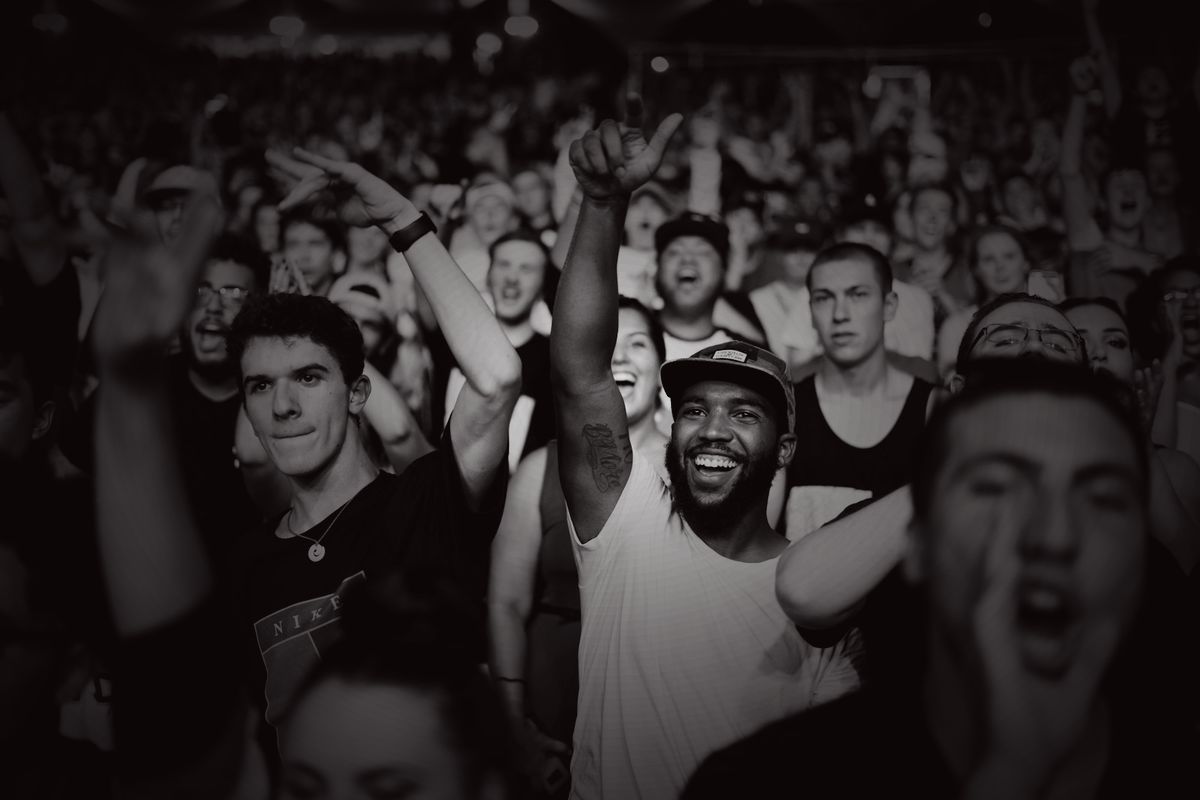 A dense crowd at a live show, faces lit by the stage