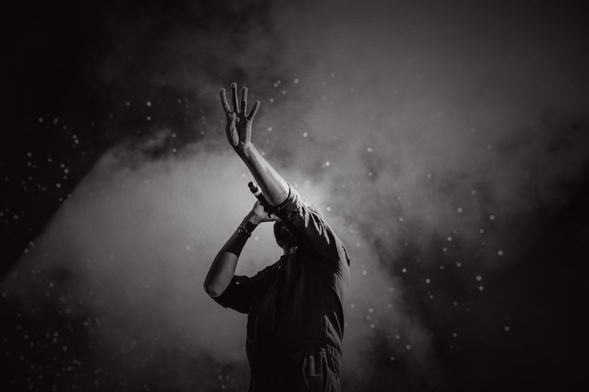 A performer alone on stage in smoke and light
