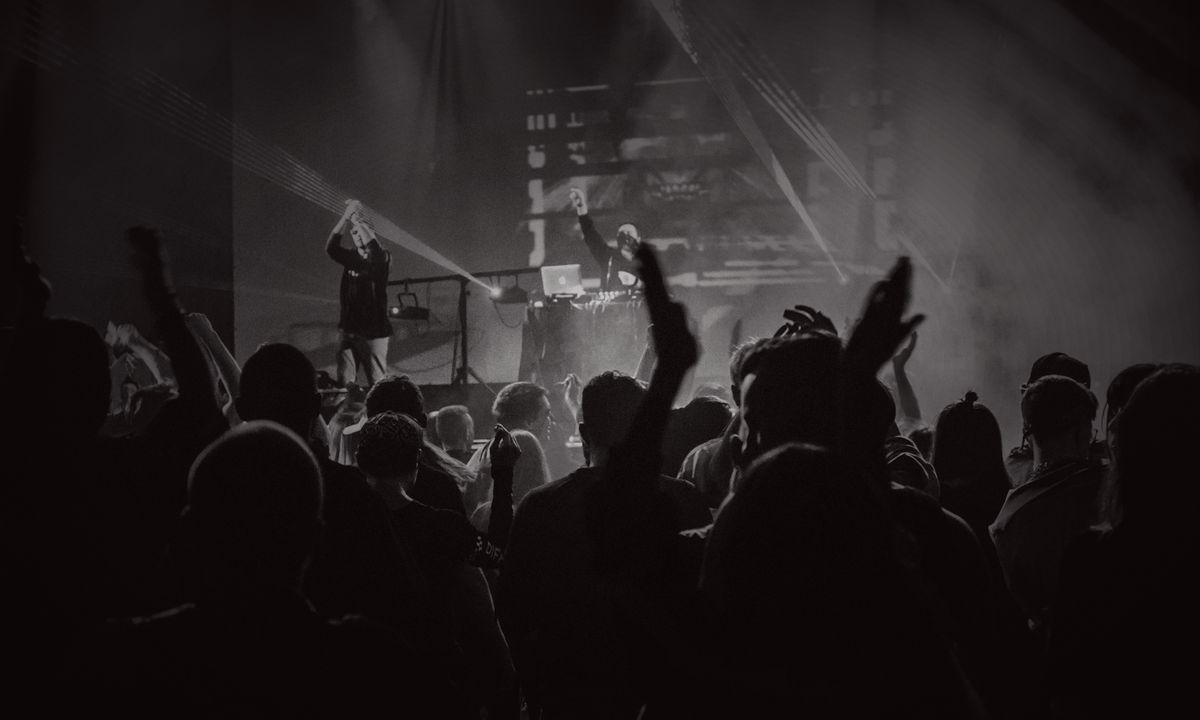 A crowd in front of a lit stage at a live show