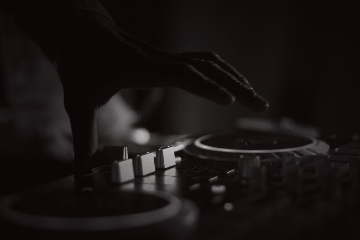 Hands working a DJ controller under stage light