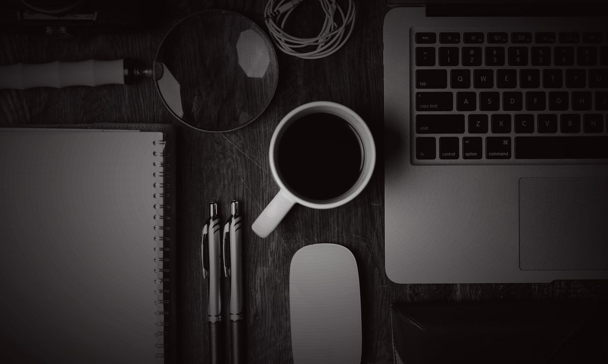 A desk with a laptop, notebook and pen laid out