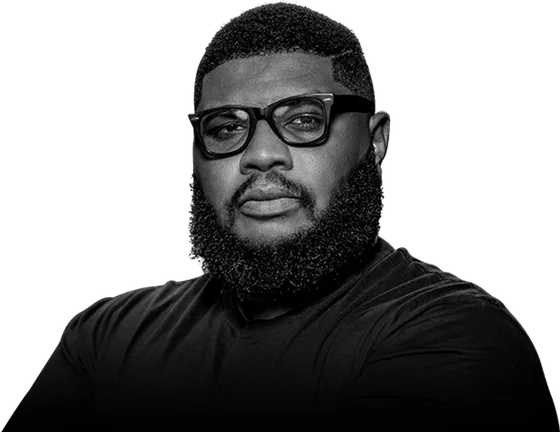 Kevin Eze, known as Xclusive Pikin, arms folded, photographed in black and white